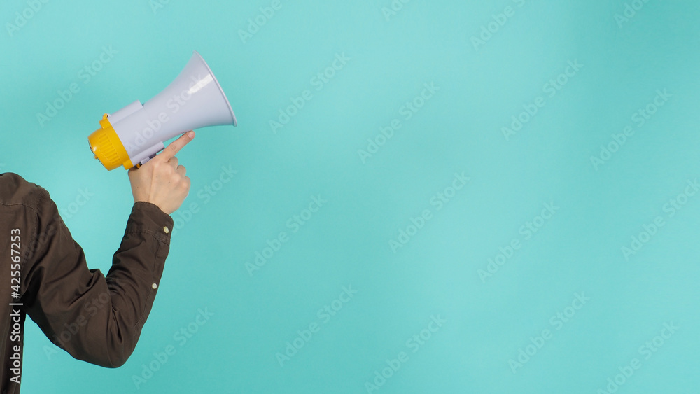 Hand is hold megaphone and wear navy color shirt on green or mint or Tiffany Blue background. Hand is hold megaphone and wear navy color shirt on green or mint or Tiffany Blue background.