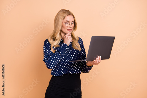 Photo of young attractive woman think thoughtful serious look laptop report project isolated over beige color background