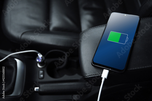 Mobile phone ,smartphone, cellphone is charged ,charge battery with usb charger in the inside of car. modern black car interior photo