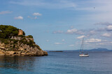the coast of majorca from sea with ancient tower and sailboat in front in  spain