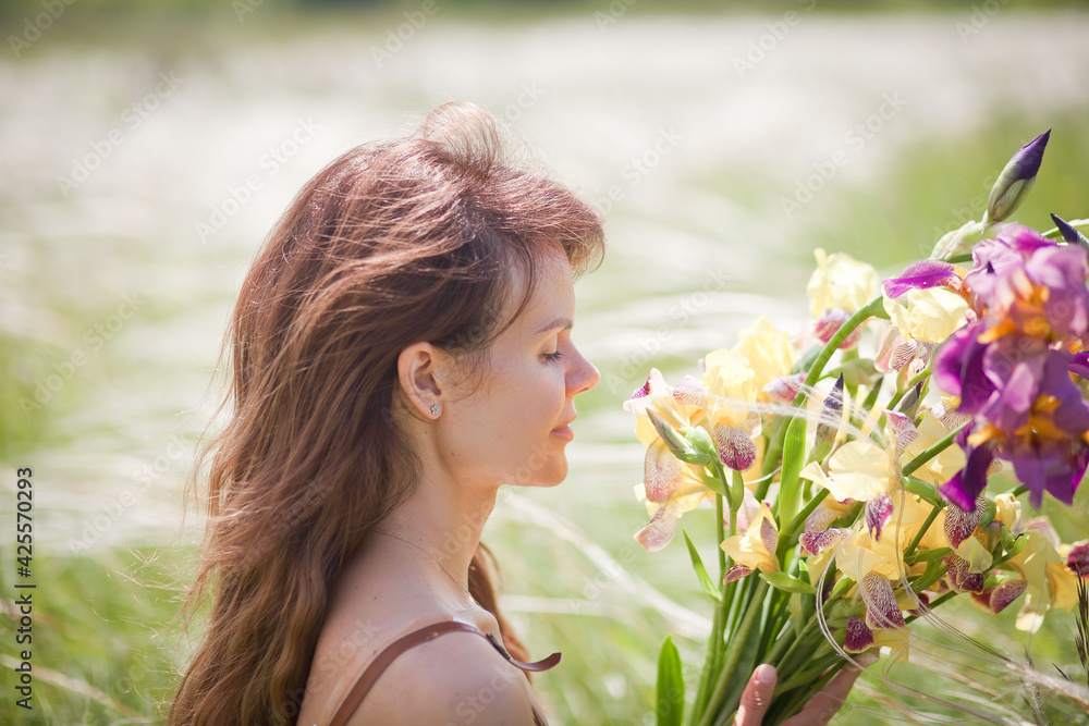 beautiful girl in a short dress walks across the field with a bouquet of irises in her hands, summer photo session, girl on vacation beautiful girl in a short dress walks across the field with a bouquet of irises in her hands, summer photo session, girl on vacation