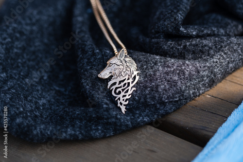 Pendant wolf head necklace golden color stainless steel shoot outside in a sunny day closeup. Selective Focus. High quality photo