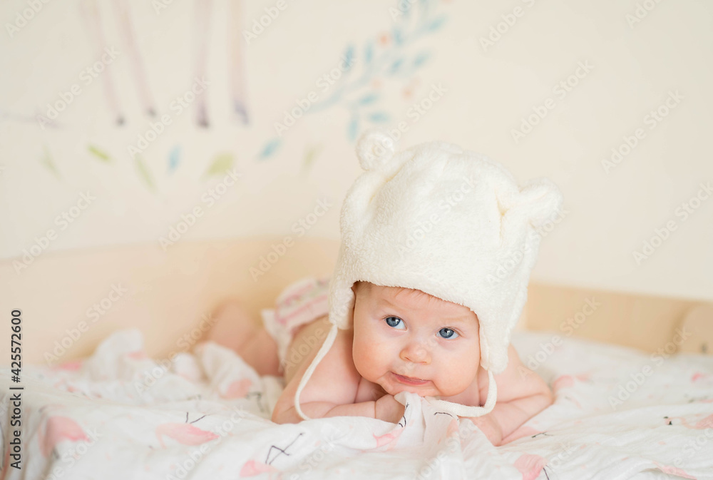 A baby wearing a bear hat lies on its stomach A baby wearing a bear hat lies on its stomach
