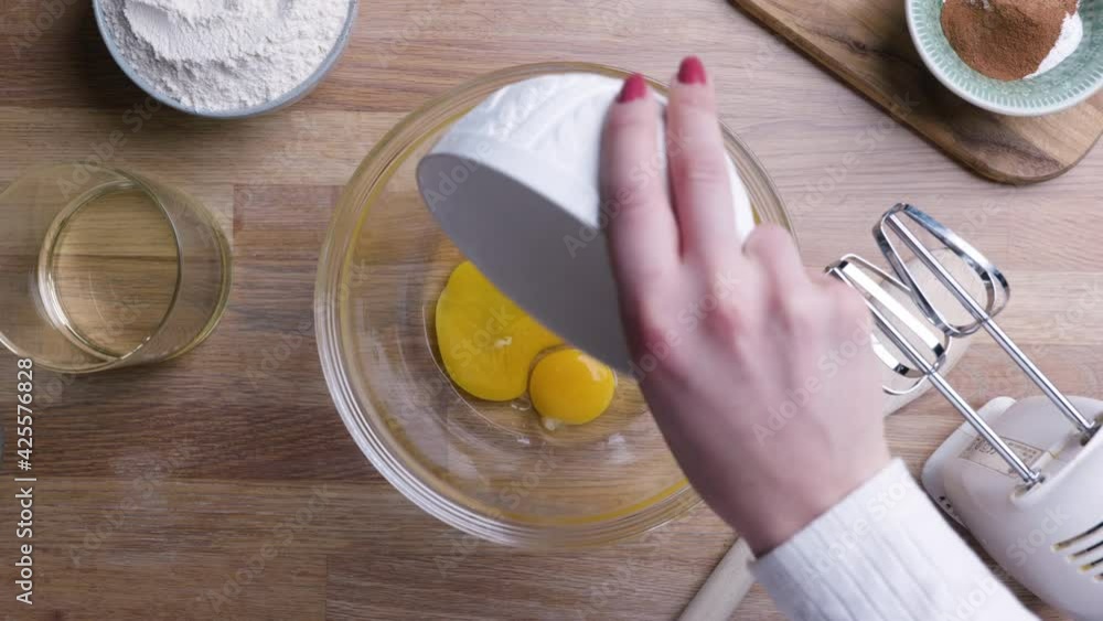 Woman Pour Eggs On Glass Bowl - Making Homemade Carrot Cake. - high angle Woman Pour Eggs On Glass Bowl - Making Homemade Carrot Cake. - high angle
