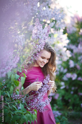beautiful girl in a short purple dress walks in the lilac garden  leather dress  lilac bloom