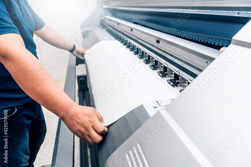 Tablou pe pânză man holding printable material on alarge format printing plotter.