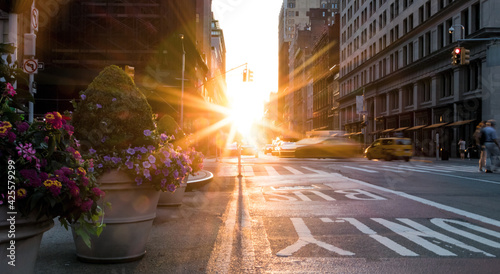 New York City busy street scene with the sun setting behind the buildings on Fifth Avenue in Midtown Manhattan