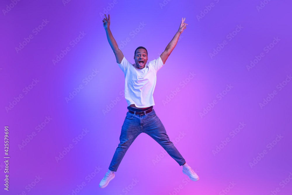 Unlimited Fun. Emotional Funny Black Guy Jumping With Hands Up, Neon Light