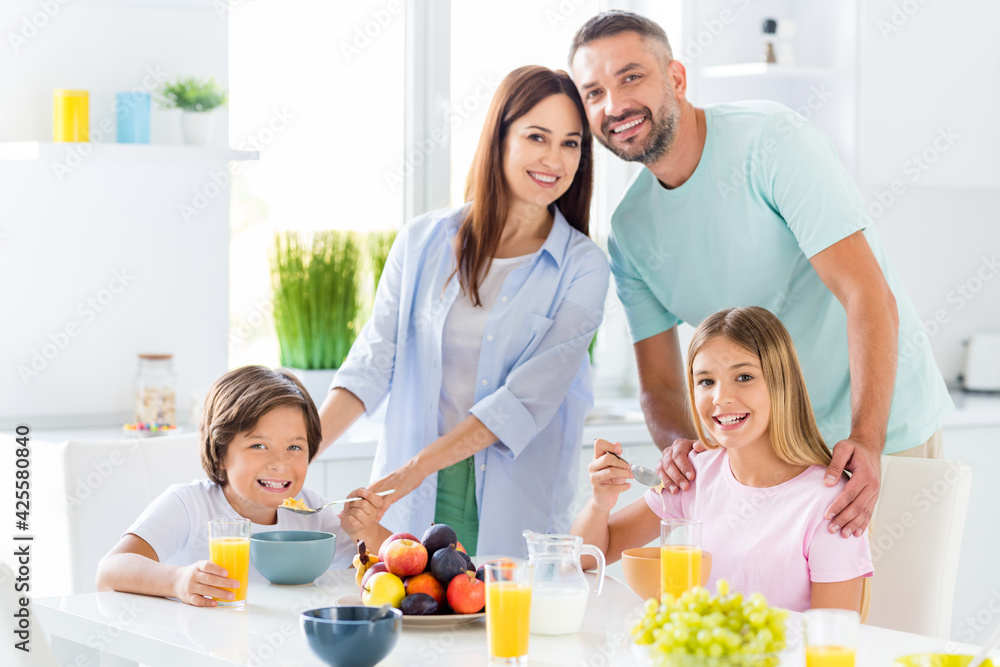 Photo portrait of family members having meal together parents embracing daughter and son eating breakfast at kitchen Photo portrait of family members having meal together parents embracing daughter and son eating breakfast at kitchen