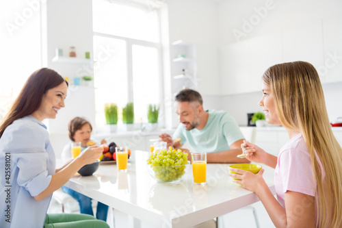 Photo of happy positive good mood family eating breakfast together drinking juice enjoying morning at home house