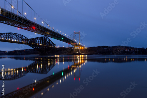 Low angle view of the 1970 suspension Pierre-Laporte Bridge and 1919 steel truss Quebec Bridge over the St. Lawrence River seen during a blue hour early morning  Quebec City  Quebec  Canada