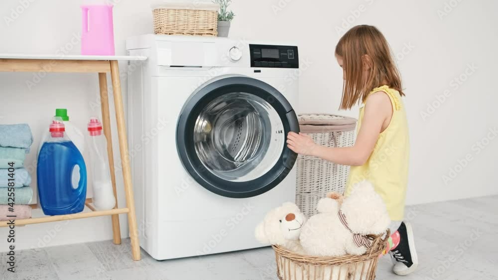 Little girl loading toys into washing machine Little girl loading toys into washing machine
