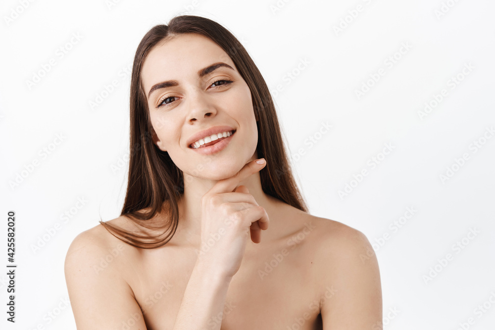 Skin care. Woman with beauty face touching healthy facial skin portrait. Beautiful smiling girl model with natural makeup touching glowing hydrated skin on pink background closeup Skin care. Woman with beauty face touching healthy facial skin portrait. Beautiful smiling girl model with natural makeup touching glowing hydrated skin on pink background closeup