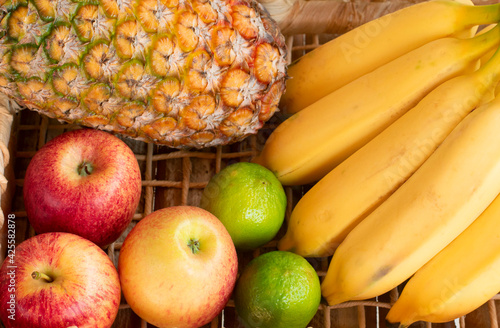 Pineapple  bananas  apples  limes in a basket