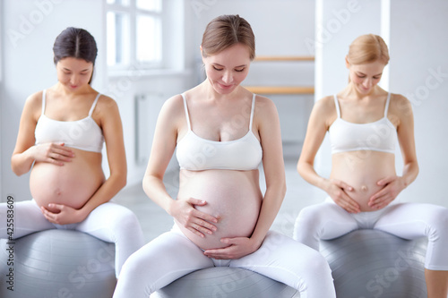 group of gravid women with big tummy sit on fitness balls relaxing