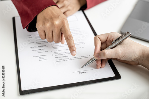 The HR department is pointing to the documents for the job applicant to sign on the contract after attending a job interview with the department manager and being selected for the job.