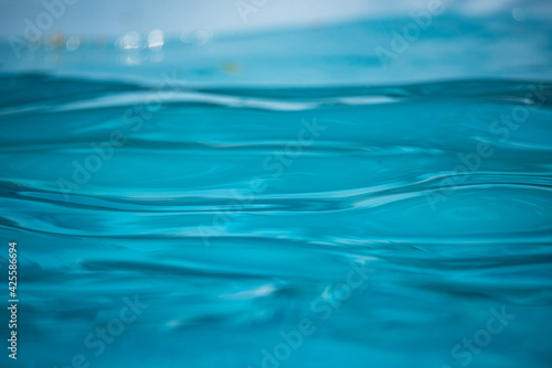 Blue water in the pool. Patterns and reflections and on the water surface. Splashing drops.