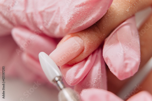 Manicure process. The master polishes the nail using an automated machine. Drill polish remover.