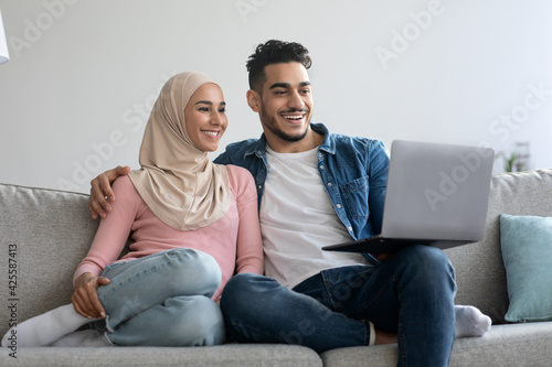 Happy young muslim family using laptop together at home © Prostock-studio