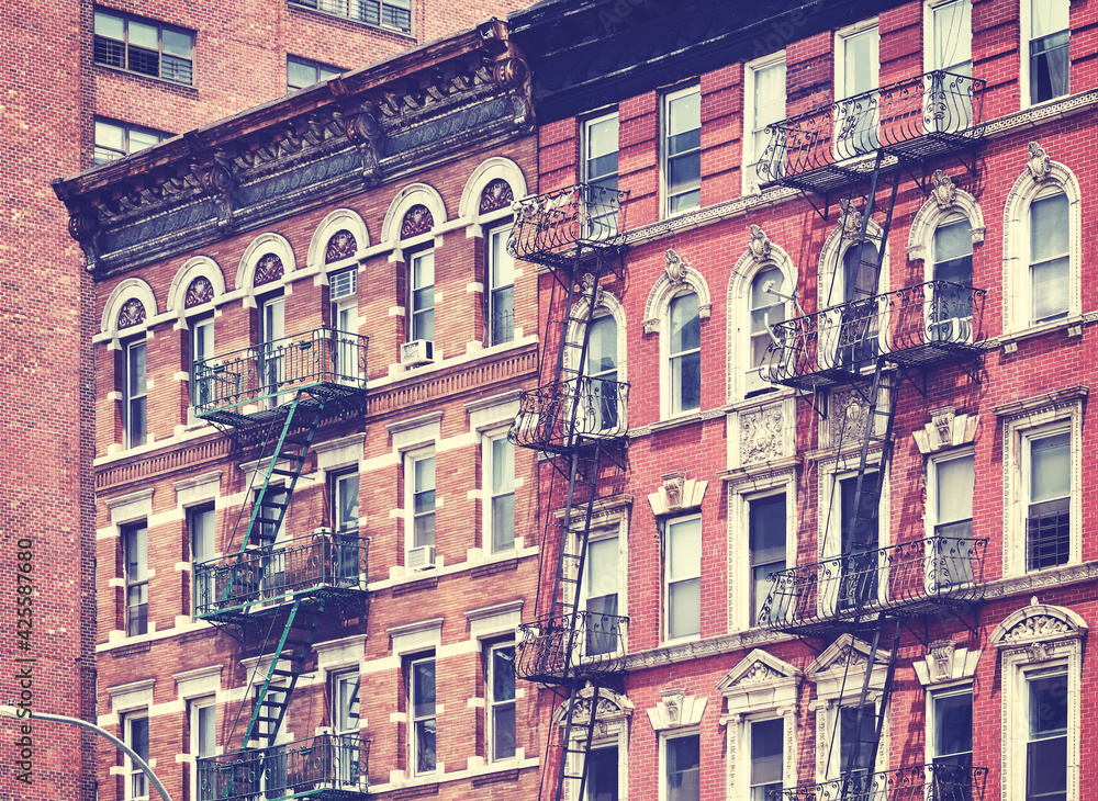 Old brick buildings with fire escapes, color toning applied, New York City, USA.