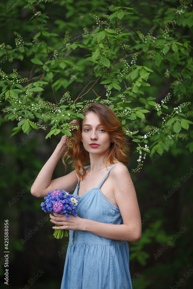 beautiful girl in a denim sundress walks with a bouquet of hyacinths in the garden, spring mood beautiful girl in a denim sundress walks with a bouquet of hyacinths in the garden, spring mood