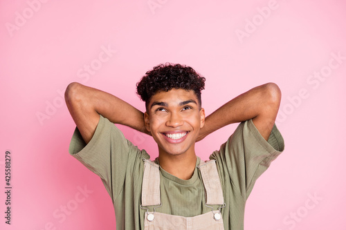 Photo of positive guy look up empty space dream relax wear beige overall isolated pink color background