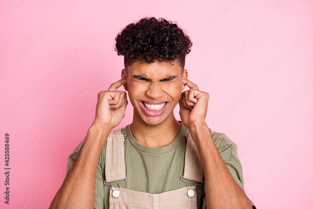 Photo portrait of african american guy plugging ears with two fingers isolated on pastel pink colored background Photo portrait of african american guy plugging ears with two fingers isolated on pastel pink colored background