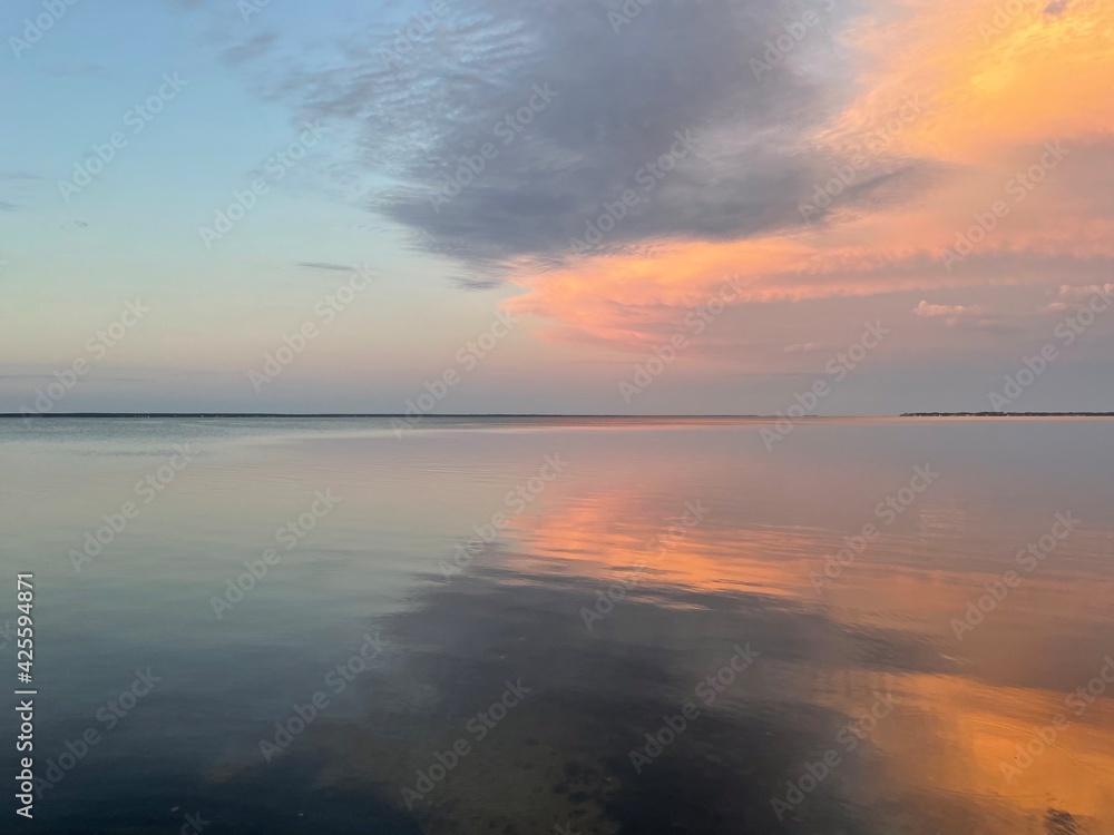 sunset over the bay with cloud reflections onto water 