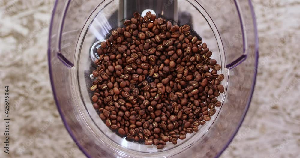 Pouring roasted coffee beans into grinder, top down view Pouring roasted coffee beans into grinder, top down view