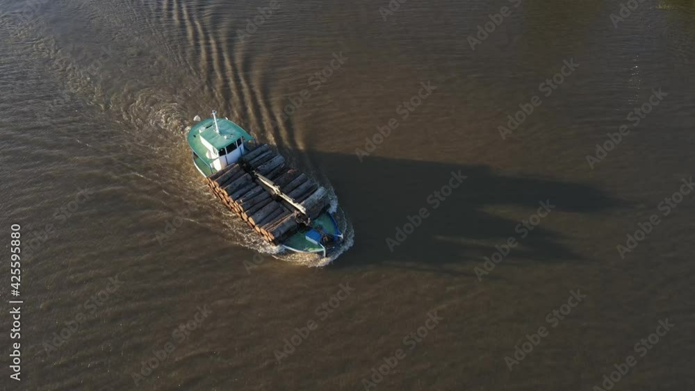 Aerial frontal tracking shot of cargo ship with wood navigating Amazon River at sunset Aerial frontal tracking shot of cargo ship with wood navigating Amazon River at sunset
