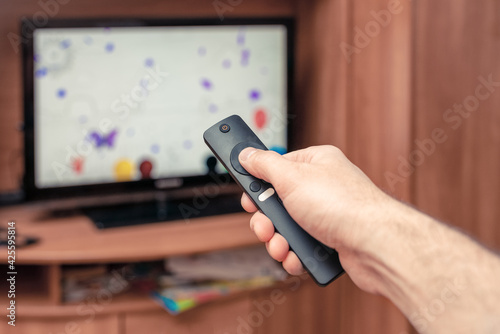 A man with a remote control in his hand is watching TV