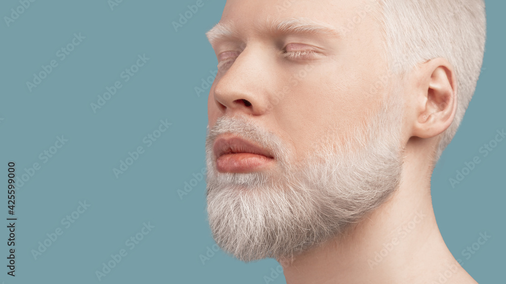 Calm bearded albino man with closed eyes resting against turquoise background, panorama with empty space Calm bearded albino man with closed eyes resting against turquoise background, panorama with empty space