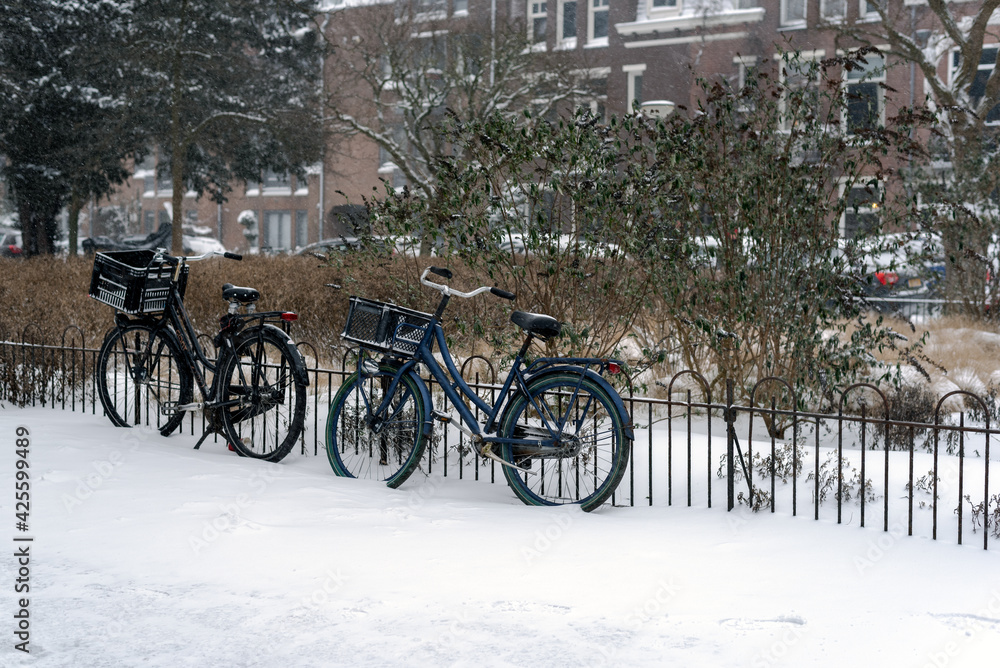 Bicycles parked by a fence on a snowy street. Amsterdam, Netherlands.