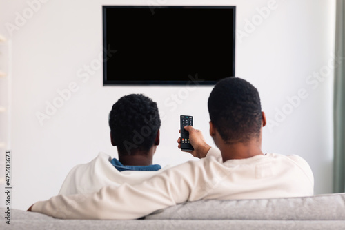 Black couple watching TV and using remote controller