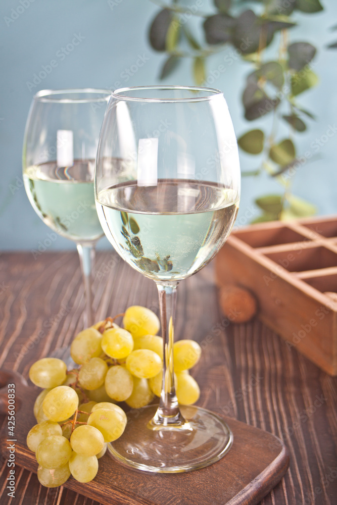 Fototapeta premium Glasses of white grape wine with grapes and wooden box on the background