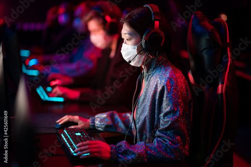 The dota 2 tournament in the conditions of covid-19 is held in medical masks, gamers play at computers, the team leader is a chinese girl