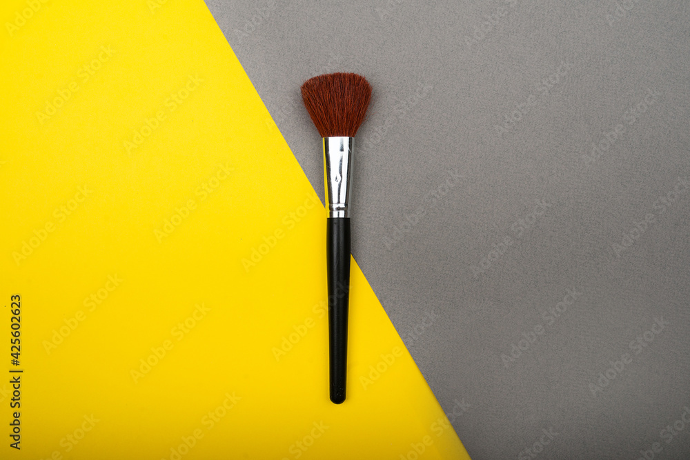 Cosmetic brush isolated on yellow and gray background. Pop-art concept. Cosmetic brush isolated on yellow and gray background. Pop-art concept.