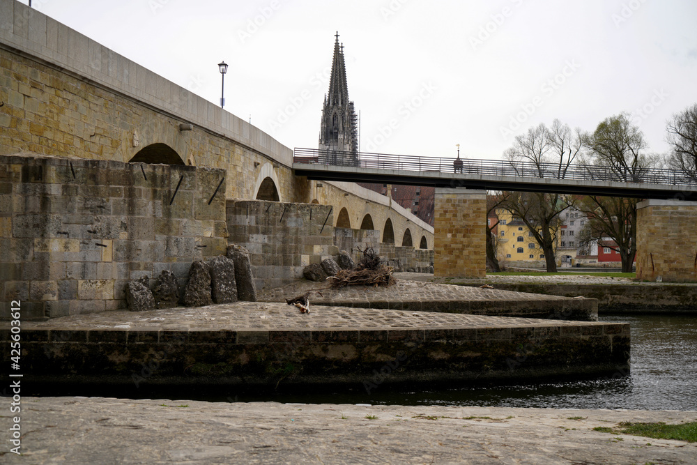 Stone bridge in Regensburg over the Danube with cathedral and Bruck Mandl