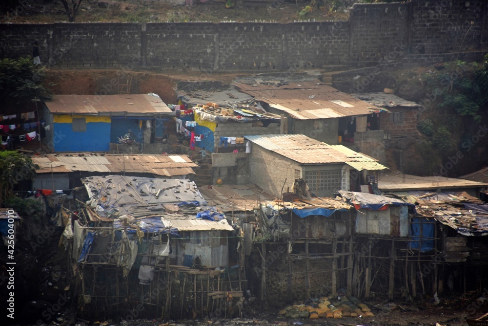 View from container terminal on shanty town in Freetown in Sierra Leone. Demolished and poor houses surrounded by garbage and wooden fishing boats in the suburb of capital, largest city.