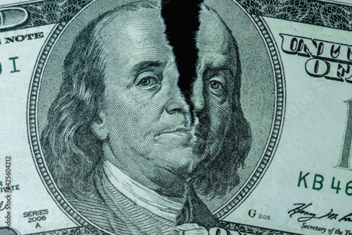 Torn one hundred US Dollar bill as symbol of global economic crisis.