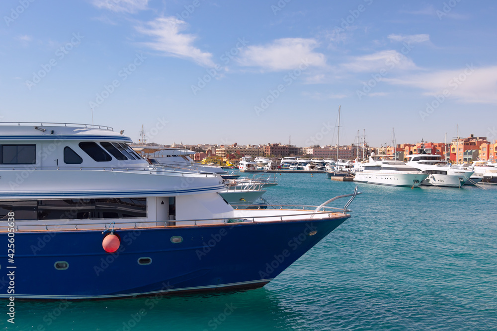 Panoramic view from the marina of Hurghada to moored yachts, boats, ships and the city's promenade with shops, cafes and a pedestrian zone for walking in the background