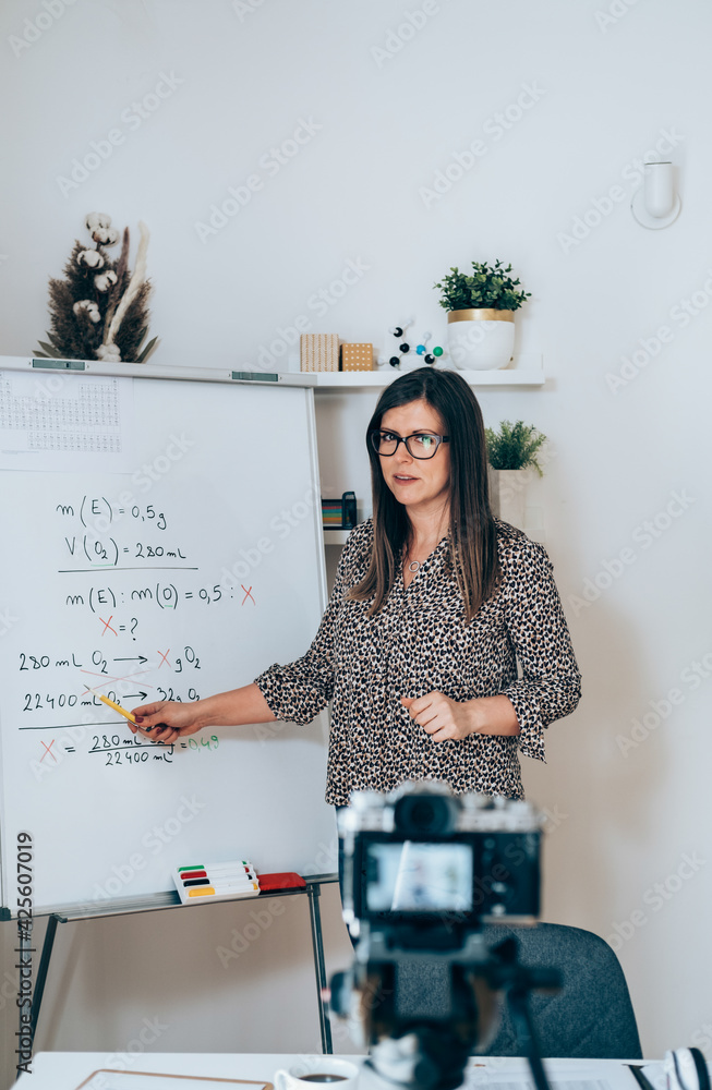 Teacher recording video tutorial for e-learning class. Female professor  standing and explaining the assignment pointing on the whiteboard and using  camera for live streaming on the internet Stock-Foto | Adobe Stock