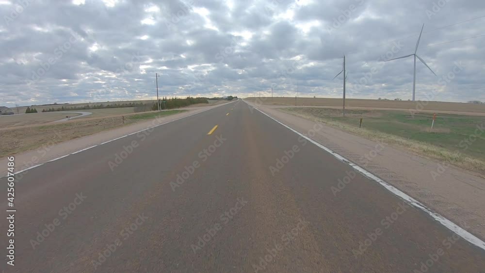 Driving on a quiet highway past wind turbines in rural southern Nebraska on a cloudy day in early spring; point of view Driving on a quiet highway past wind turbines in rural southern Nebraska on a cloudy day in early spring; point of view