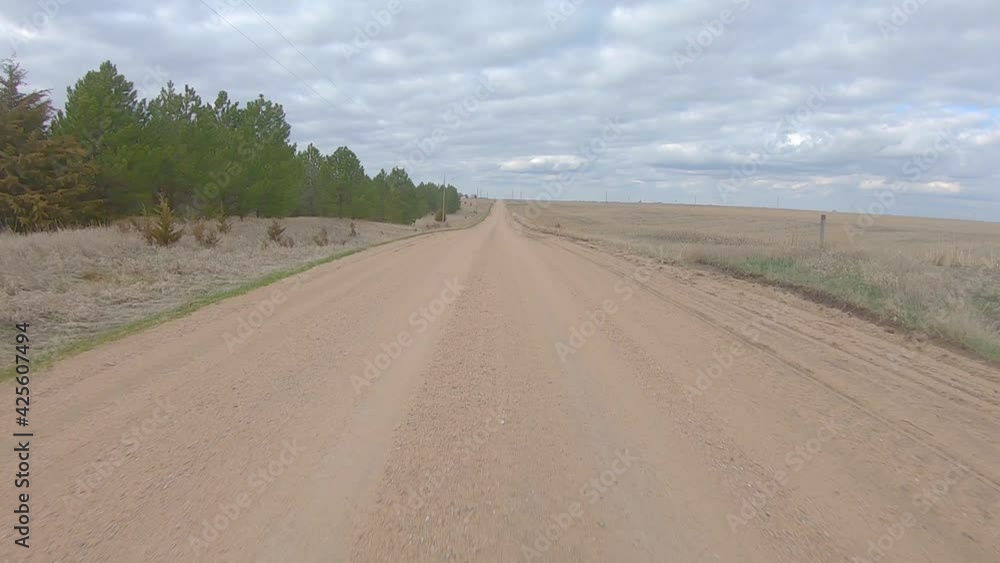 Point of view driving on a straight stretch of gravel road in rural Nebraska on a cloudy winter day; lonely road Point of view driving on a straight stretch of gravel road in rural Nebraska on a cloudy winter day; lonely road