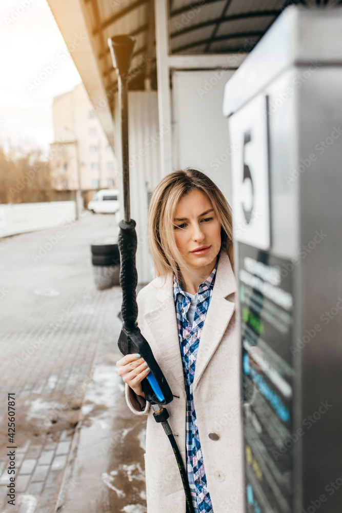 Naklejka premium A blonde woman washing a red car