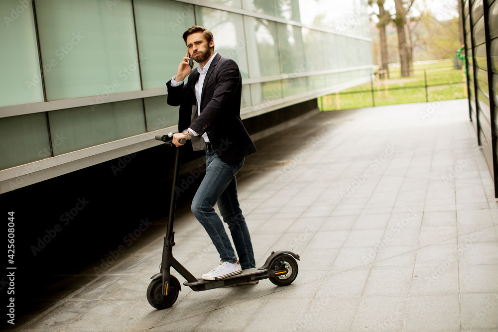 Young businessman using mobile phone on electric scooter Young businessman using mobile phone on electric scooter
