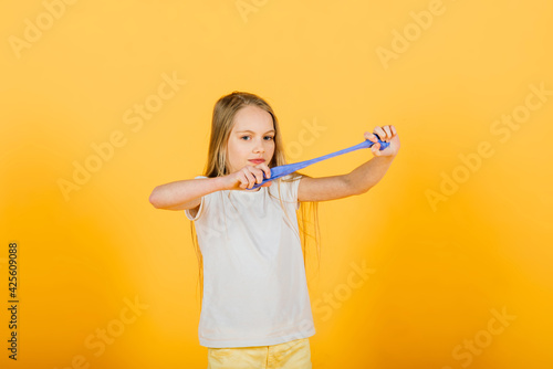 Young girl playing with blue slime on yellow background
