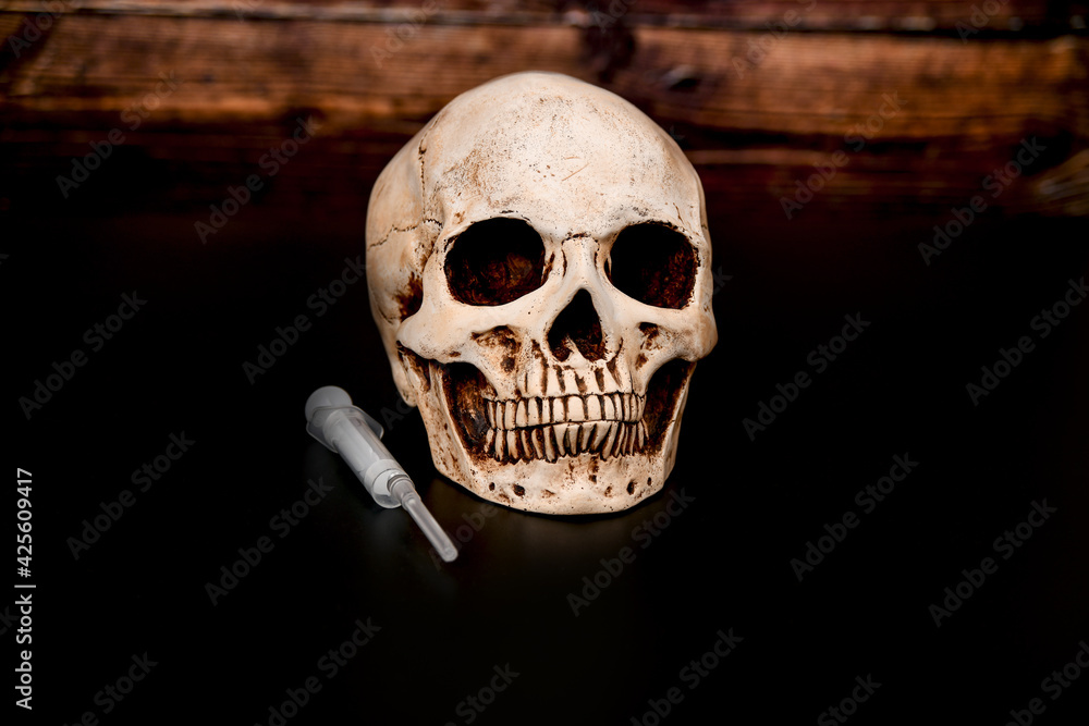 Skull and syringe on a dark wooden background. Skull and syringe on a dark wooden background.