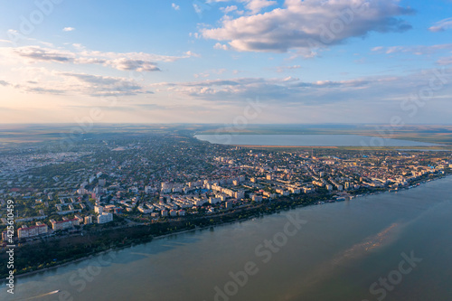 Aerial view of Galati City, Romania. Danube River near city with sunset warm light © Daniel CHETRONI