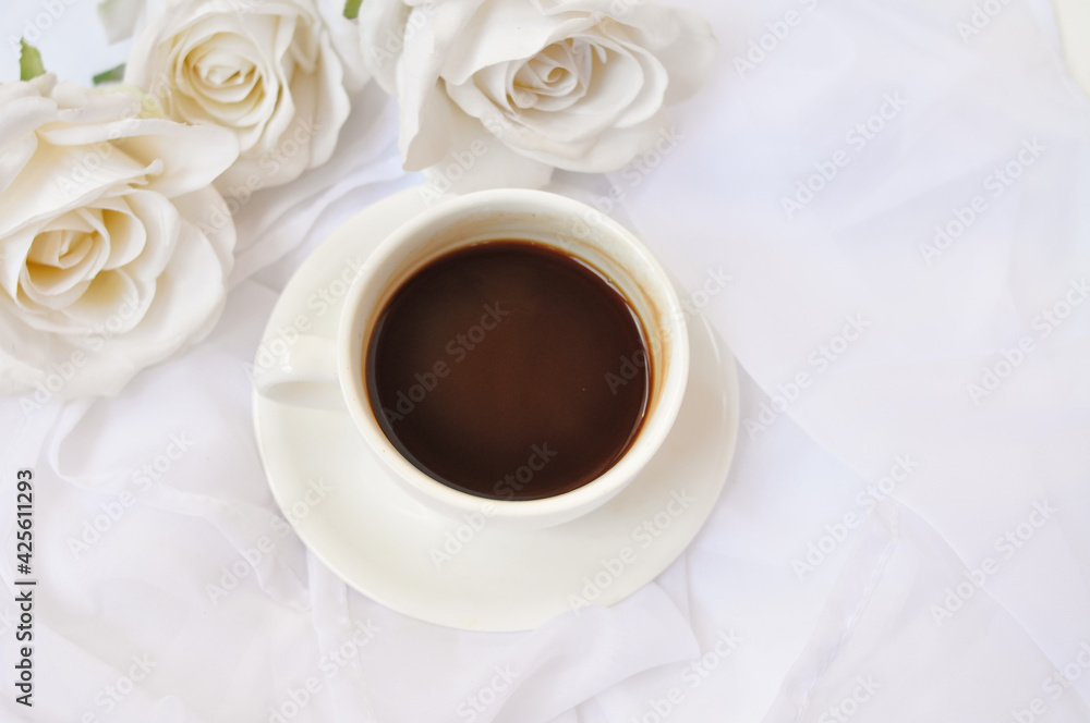 Obraz premium cup of coffee with white roses in the morning